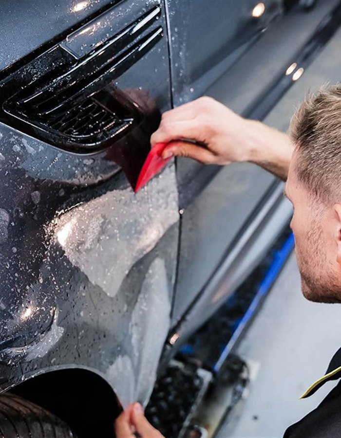 Paint protection film being applied to a car body panel